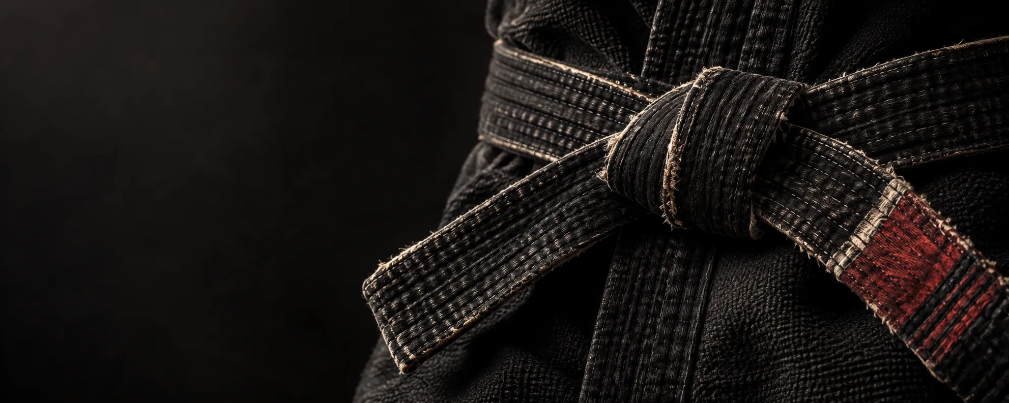 Close-up of a worn black jiu-jitsu belt and gi fabric